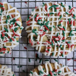 Cookie with Christmas colored sprinkles and white frosting sits on wire cooling wrack